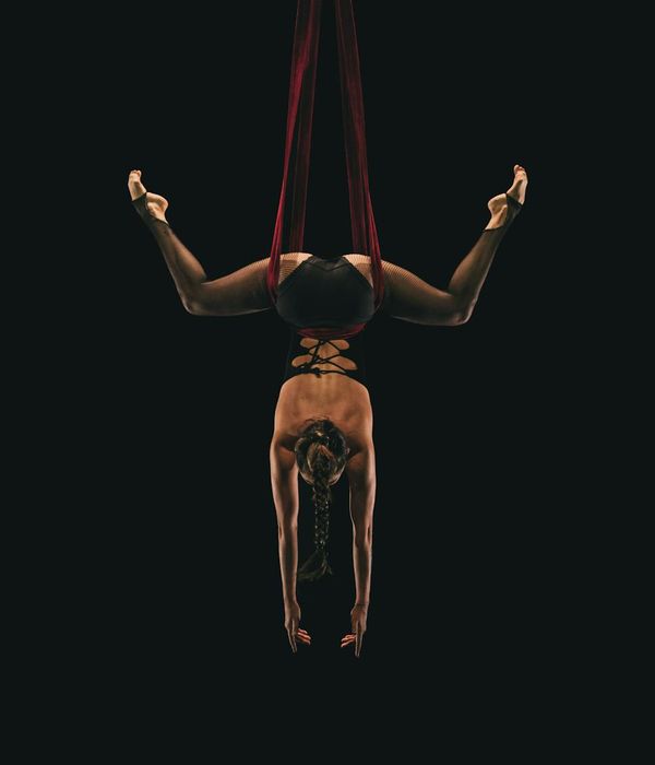 Woman in a graceful yoga pose against a dark slate background.